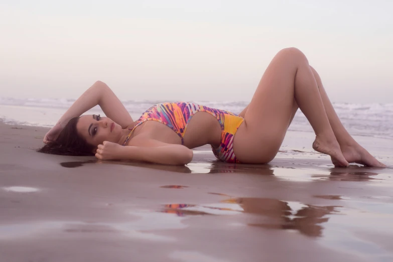 a woman is lying on the beach wearing a swim suit