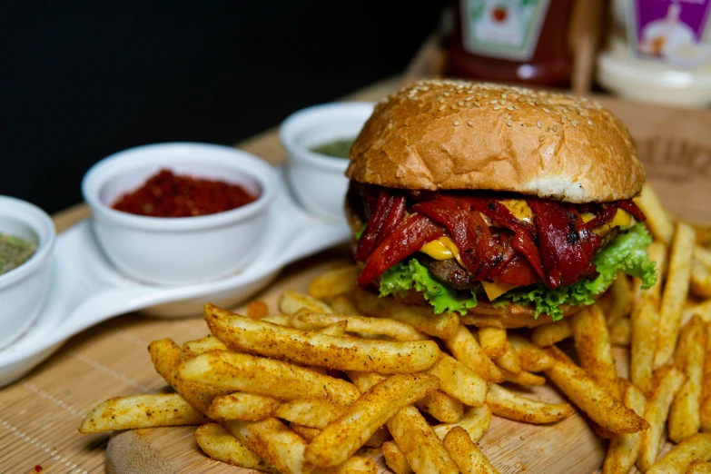 burger sitting on top of a wooden plate with fries