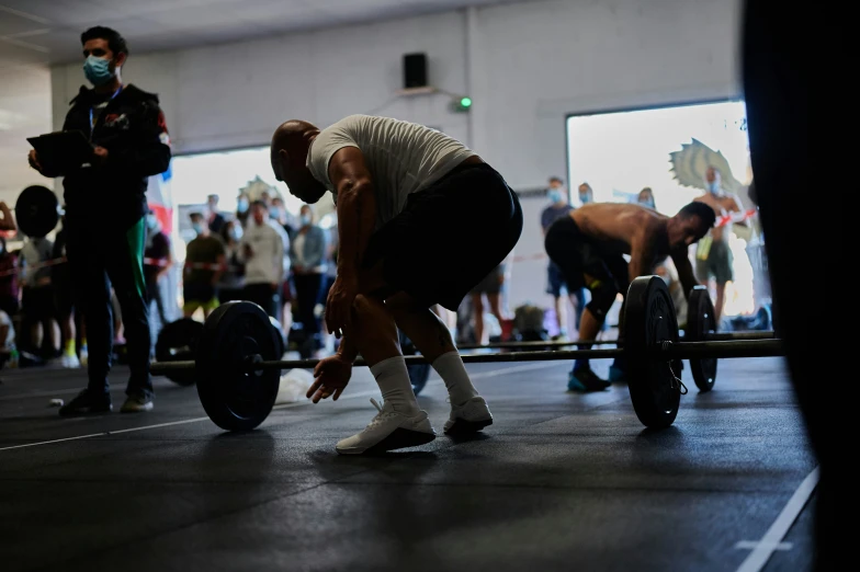 a man squats on his knees in front of other people at the crossfit gym