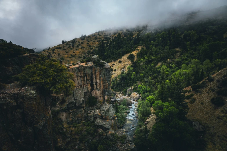 a cloudy mountain landscape shows a narrow river in the valley between cliffs