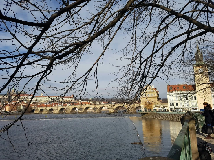 a man and woman walking on a bridge next to a body of water