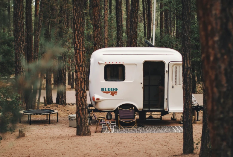 a camping trailer sits next to some trees