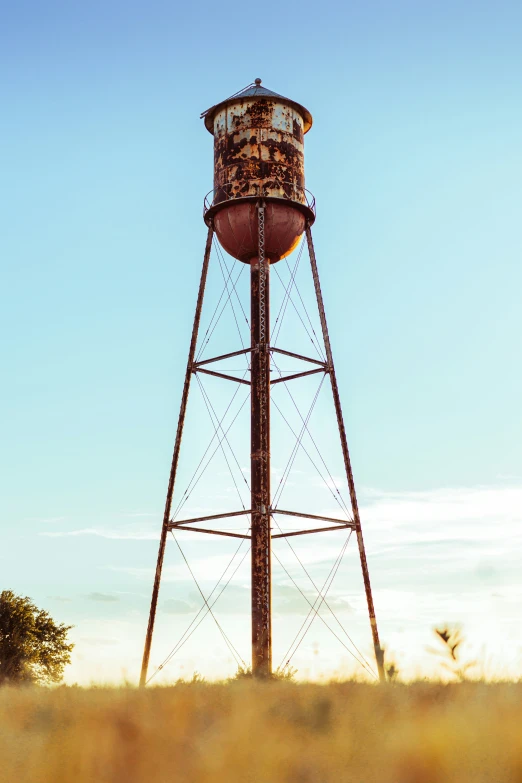 a old rusty water tower sitting in a field