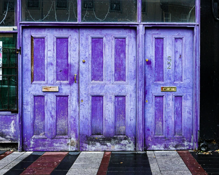 purple doors sitting outside of a building next to a window