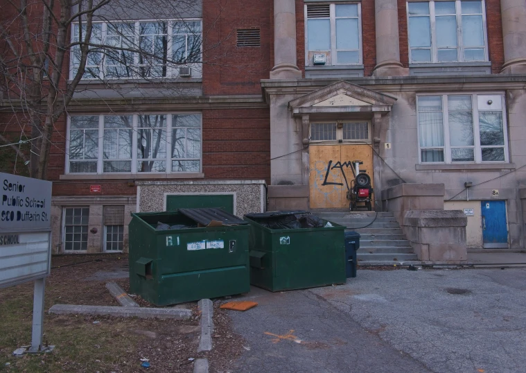 two bins on the pavement in front of a large building