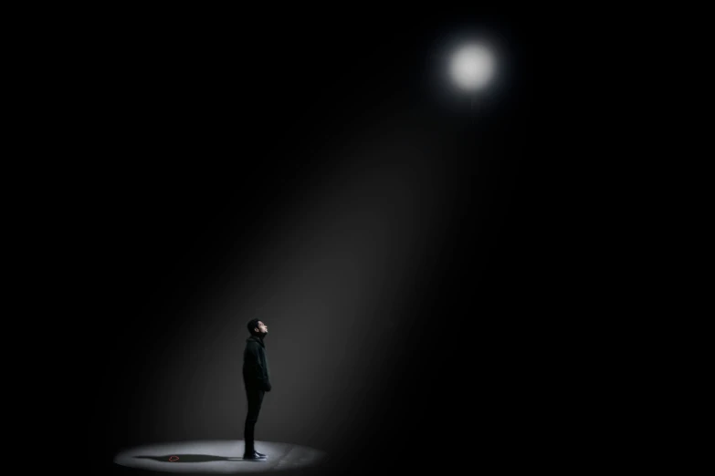 person standing in the dark looking at a light