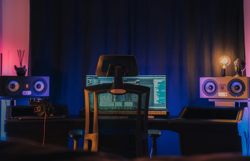 a laptop sits at a desk with sound equipment in the background