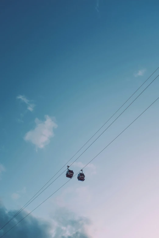 a cable car with three passengers passing overhead on a cloudy day