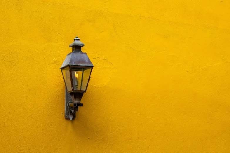 there is a old fashioned lamp against a yellow wall