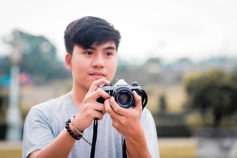 a young man holding a camera up to the camera lens