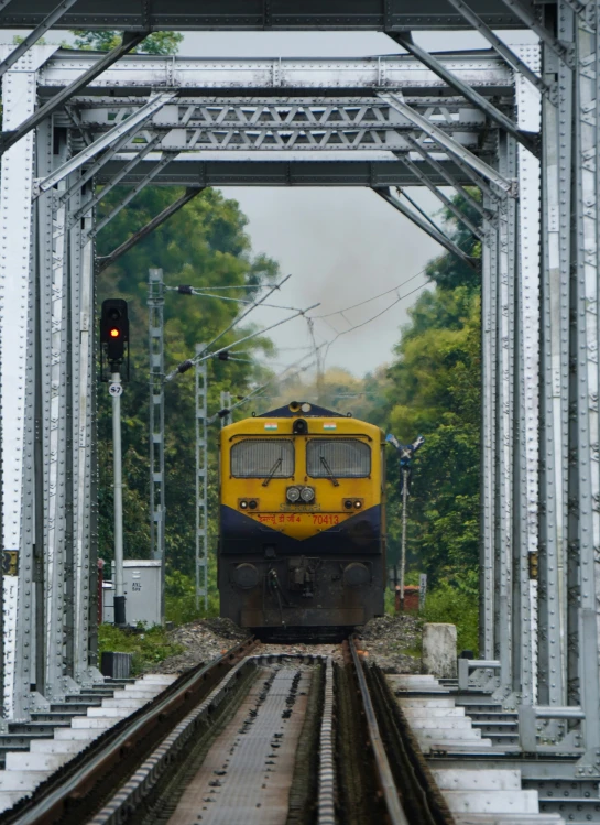 a yellow and blue train passing under an overpass