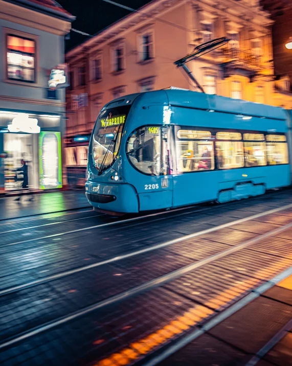 a long tram going down a street in a city at night