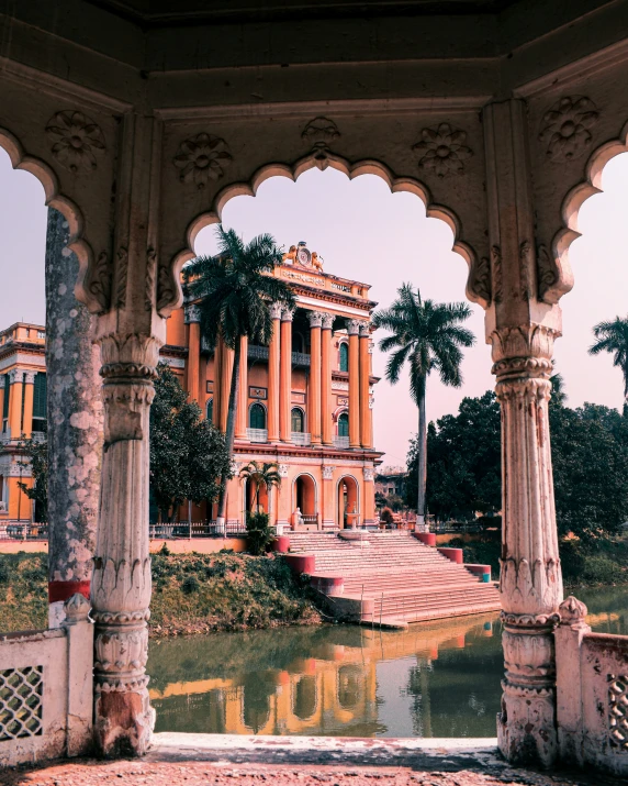 a large building with columns around it with water in the foreground