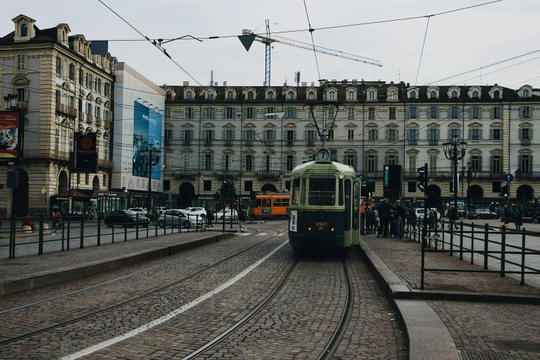 a green train passing by a tall building