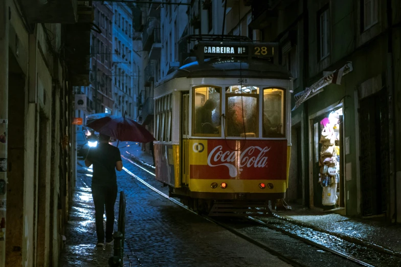 a streetcar with an open umbrella passing through an alleyway