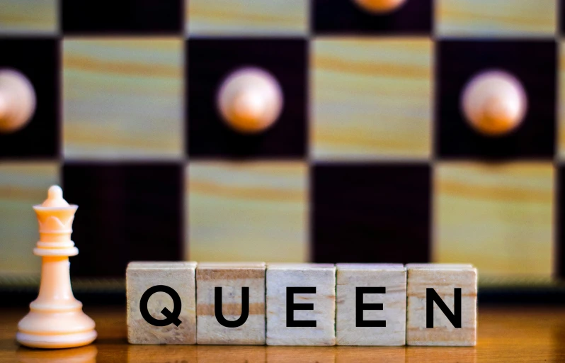 cube blocks spelling the word queen and a chess piece