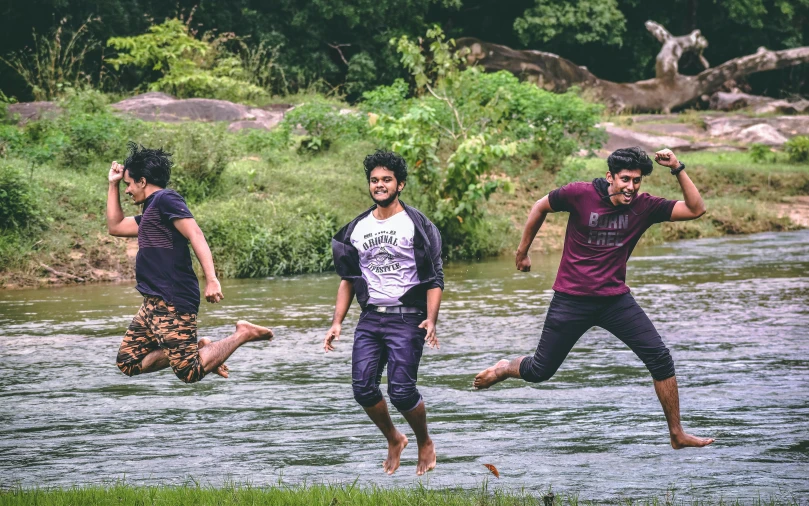 four people jumping into a river while one catches a frisbee