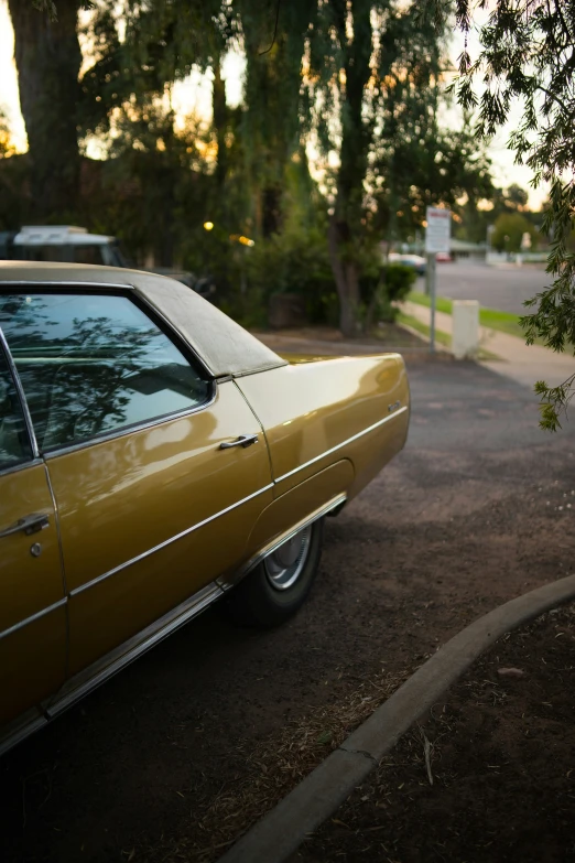 a yellow car is parked by a tree