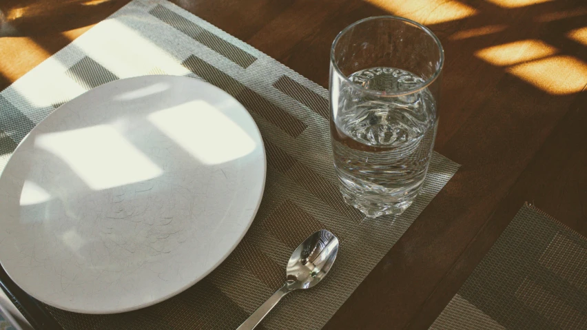 an empty plate on the table next to a glass