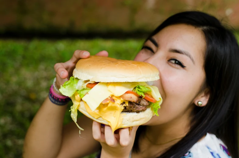 a woman is biting into a large hamburger