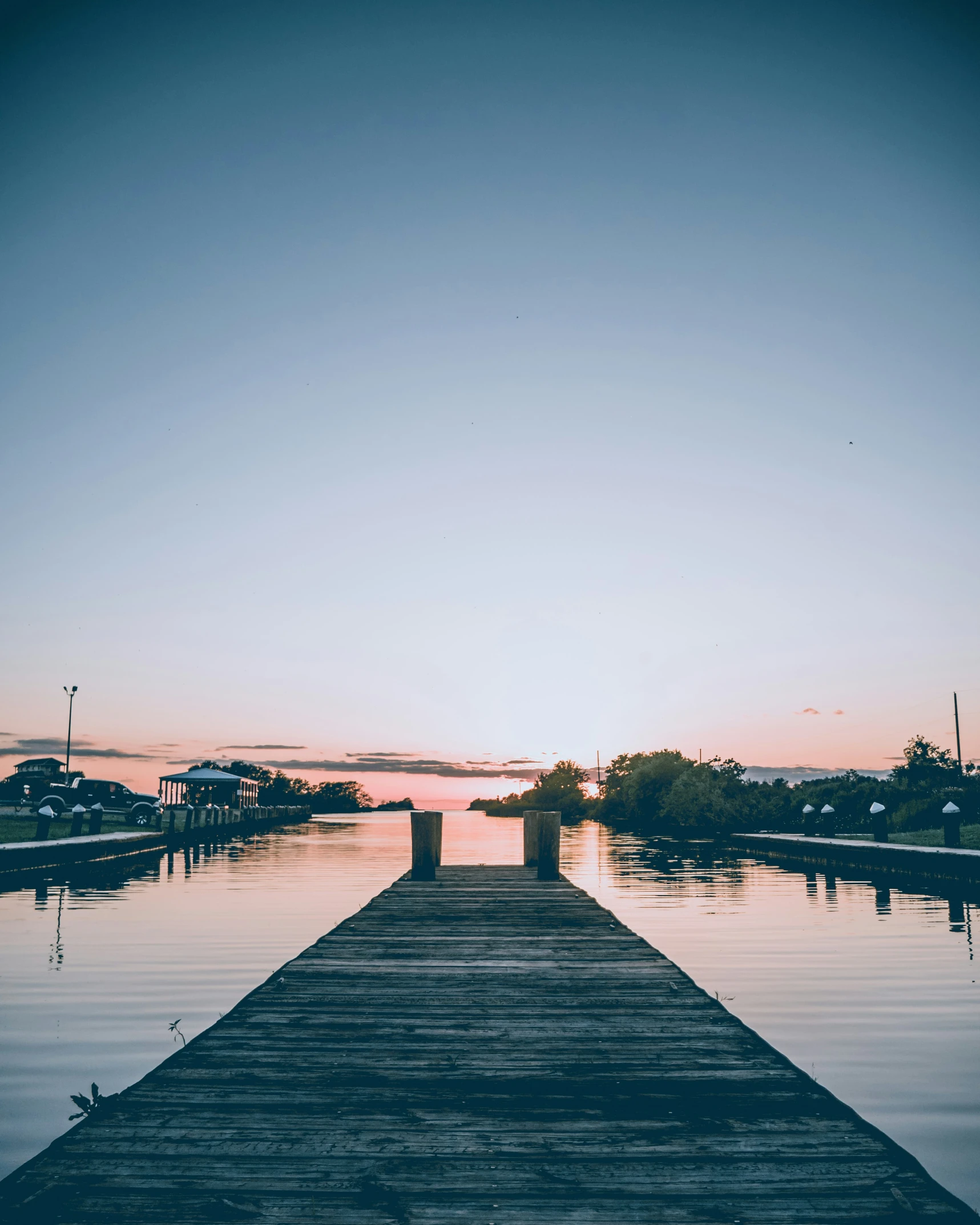 a pier with water and the sun setting in the background