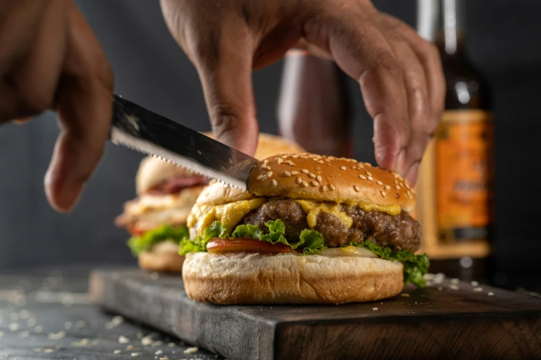 a hand with a knife cuts into a burger