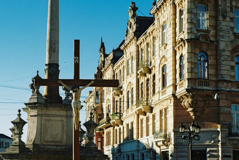 an ornate statue stands in front of a building with a large cross on it