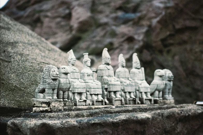 a long row of statues of men sitting in front of a mountain