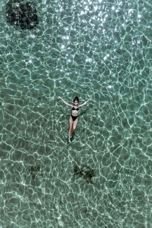 a girl in a bikini swims under the waves in clear blue water