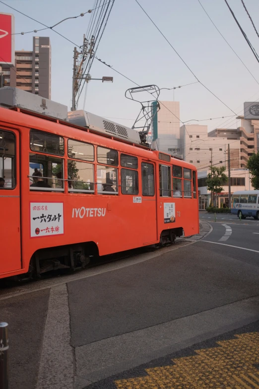 an orange train sits on a city street