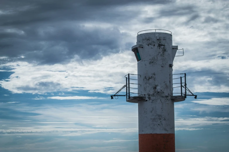 a large white and red lighthouse against a cloudy sky