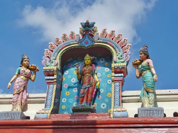 three statues of deities are on top of the statue