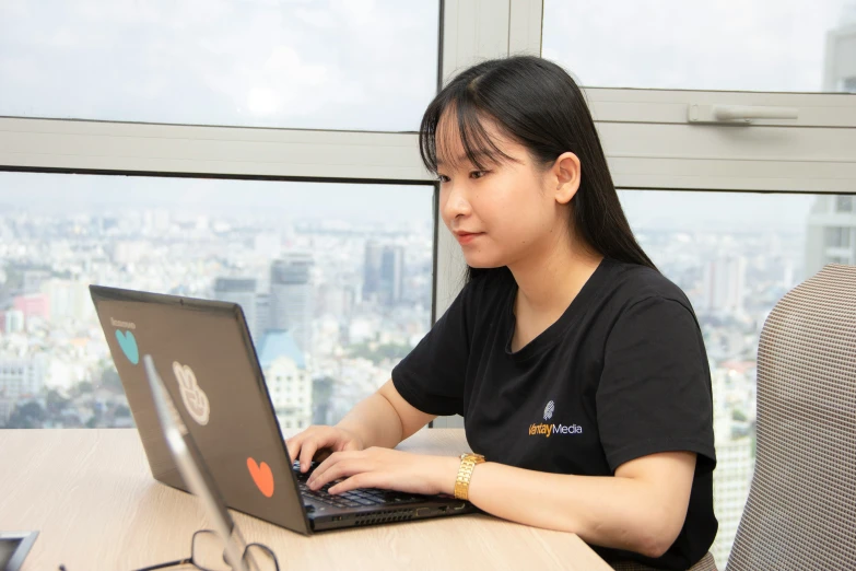 an asian woman with a laptop and view of the city