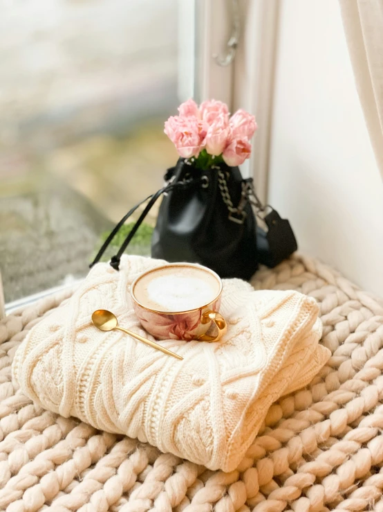 a cup of tea on a pillow next to a bag