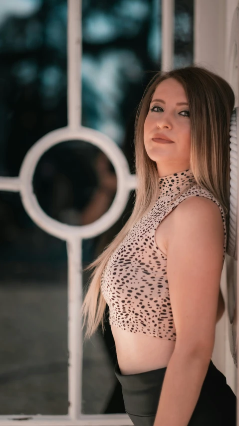 a beautiful woman posing with a glass window in the background