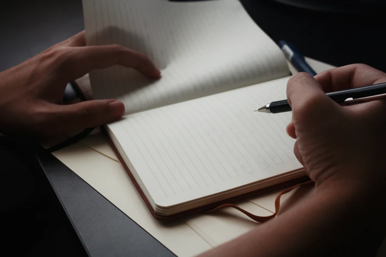 a person writes on a notepad while using a pen