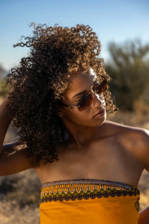 a woman wearing an orange and yellow dress and sunglasses