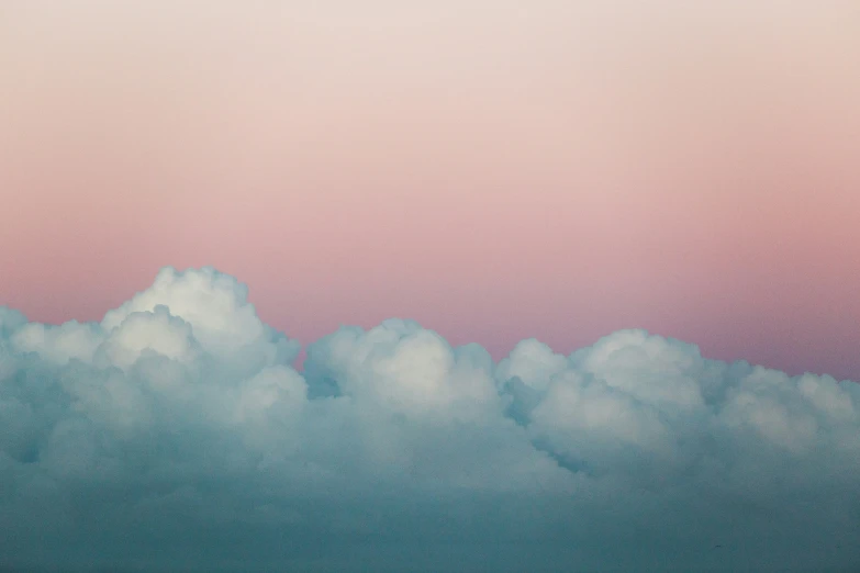 the plane flies over some pink clouds in the sky