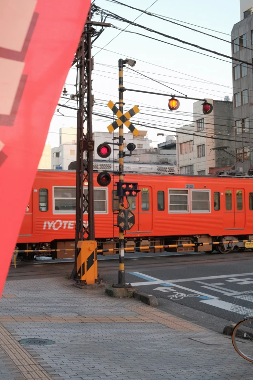 a red train sitting next to two orange railroad tracks