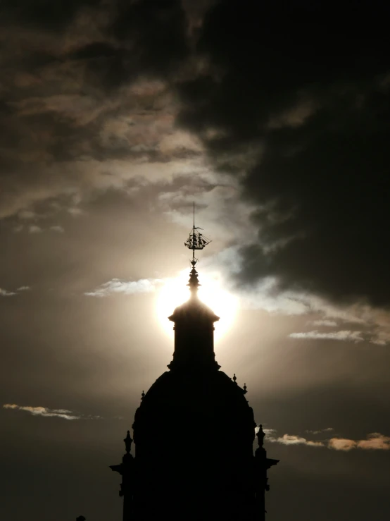 a sun is seen in the sky behind a clock tower