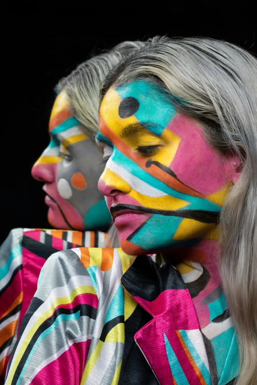 two women are wearing face paint and colorful clothing