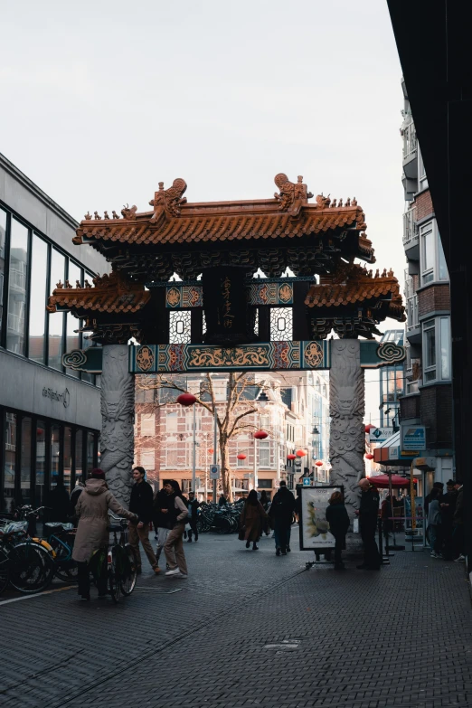 several people walking past a chinese style arch