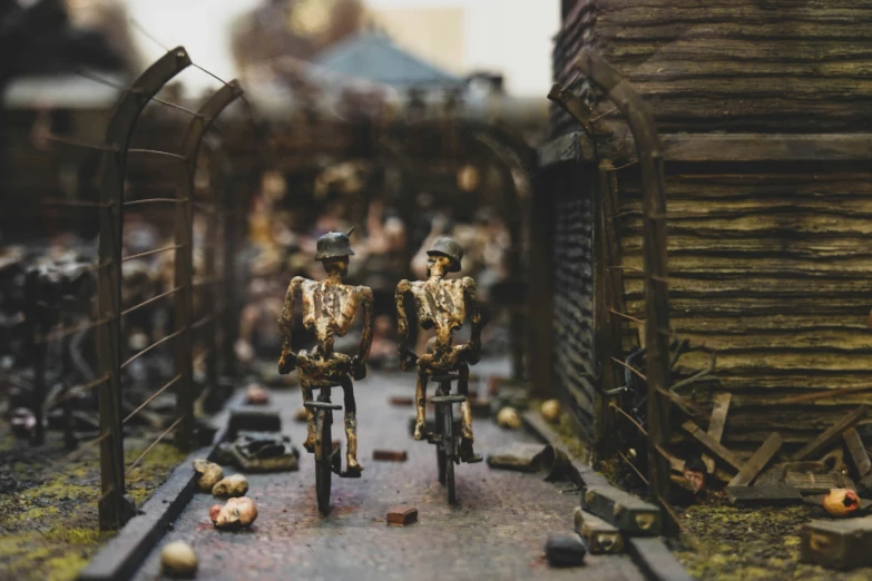 two miniature statues of people on a road with bicycles