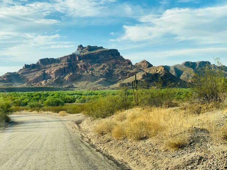 a scenic mountain scene with a road leading to the mountains