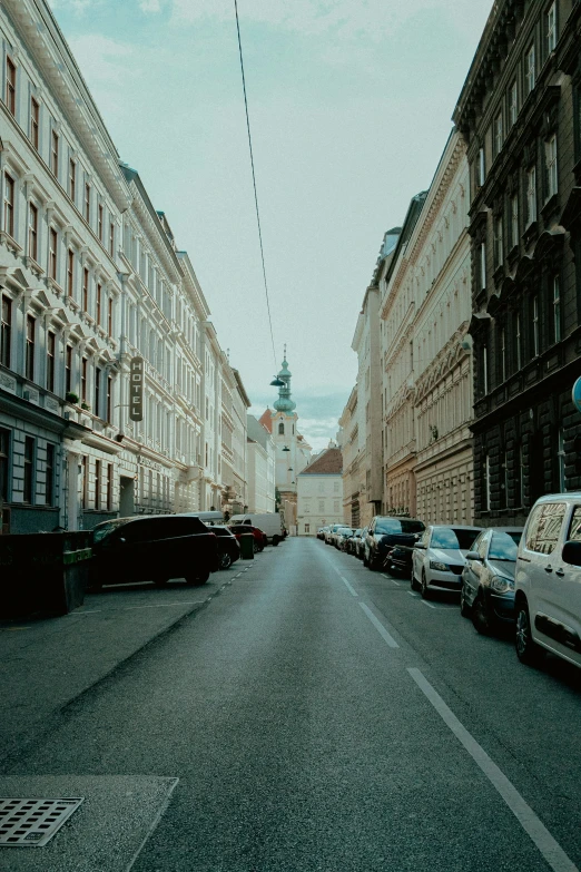 many cars are parked in a row on the side of a city street