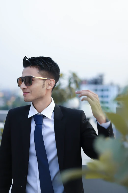 a man wearing glasses and a suit on a balcony