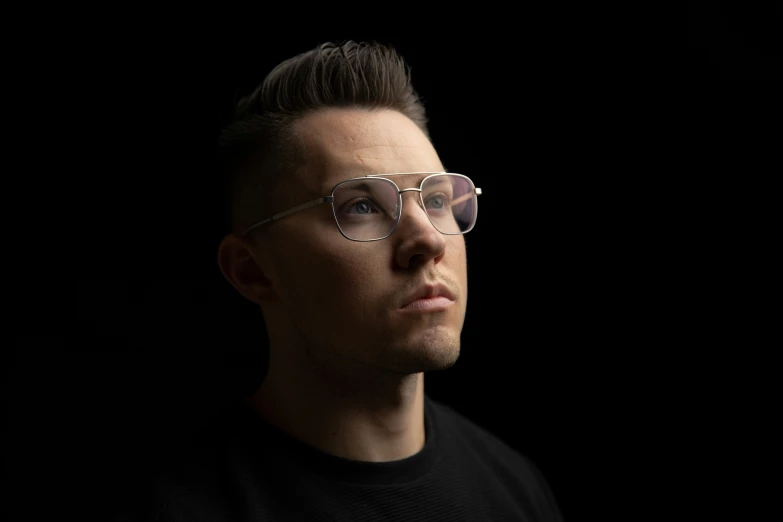a man with glasses staring into the distance