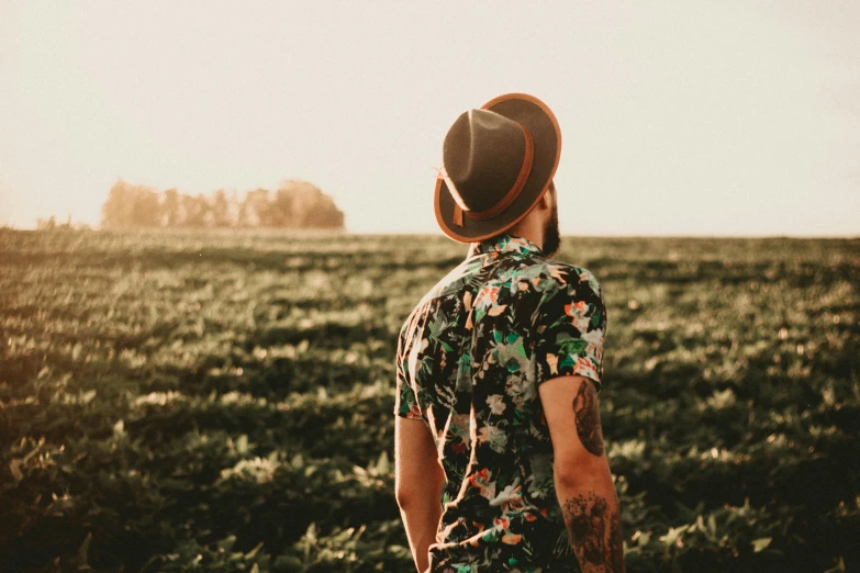 a man stands in the middle of a field, with his arms in the air