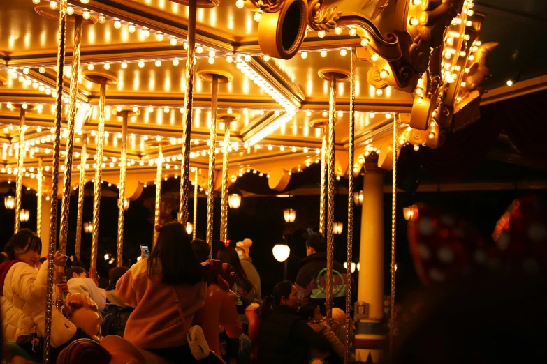 people stand on the carousel at night near many lights