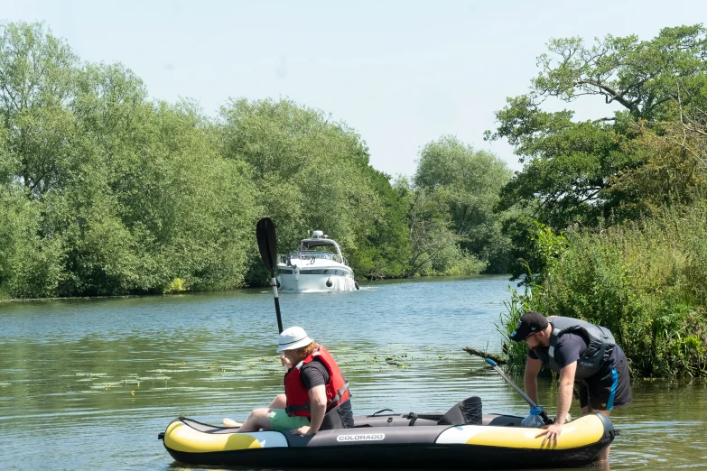 two men in boats are in the water next to trees